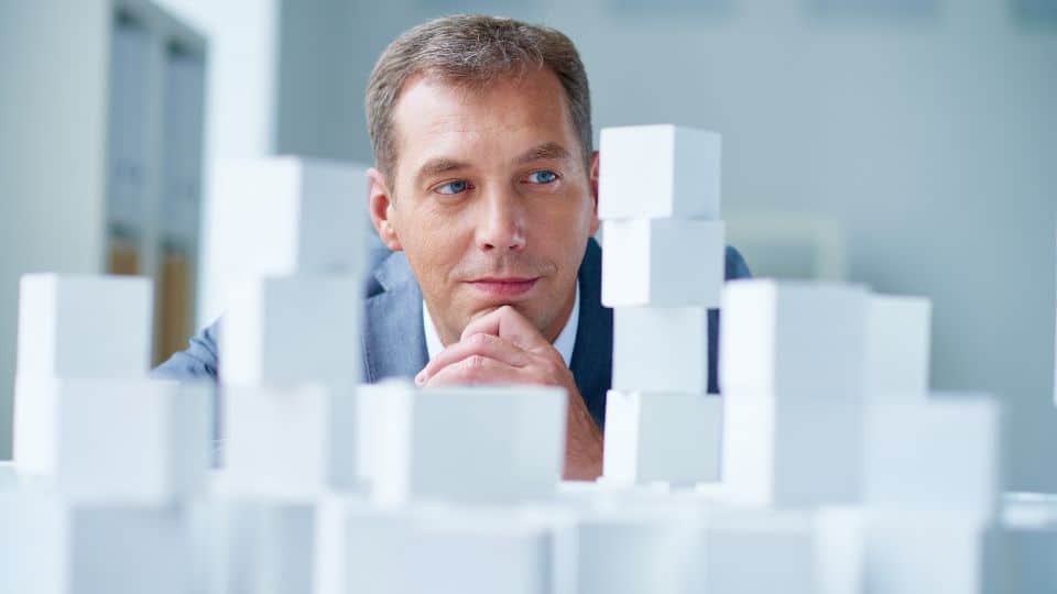 Business owner thinking about a business strategy that he will build in front of white miniature blocks.