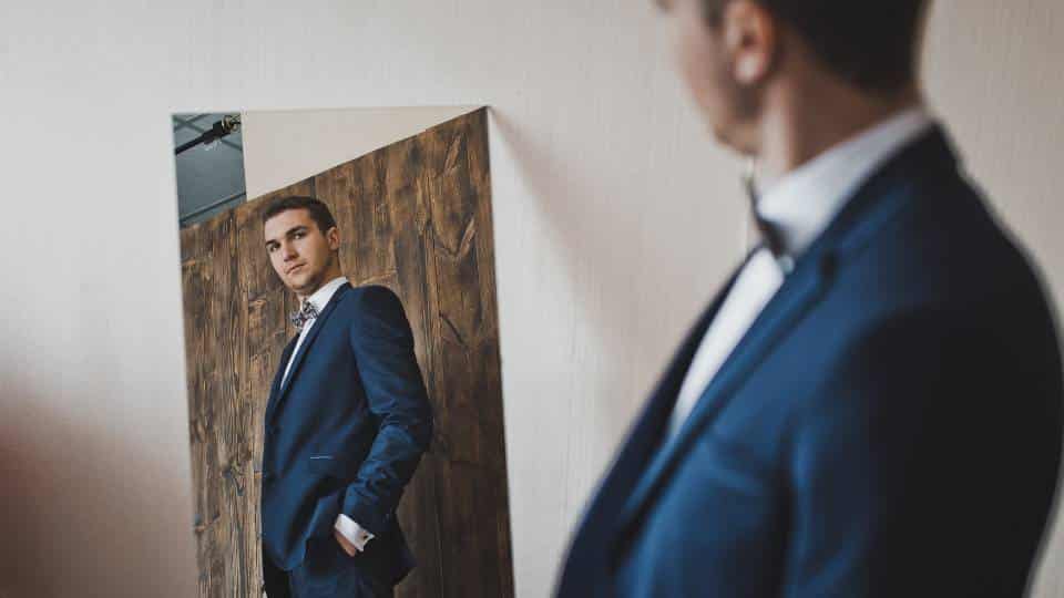 A business owner in blue suit looking at himself in front of the mirror